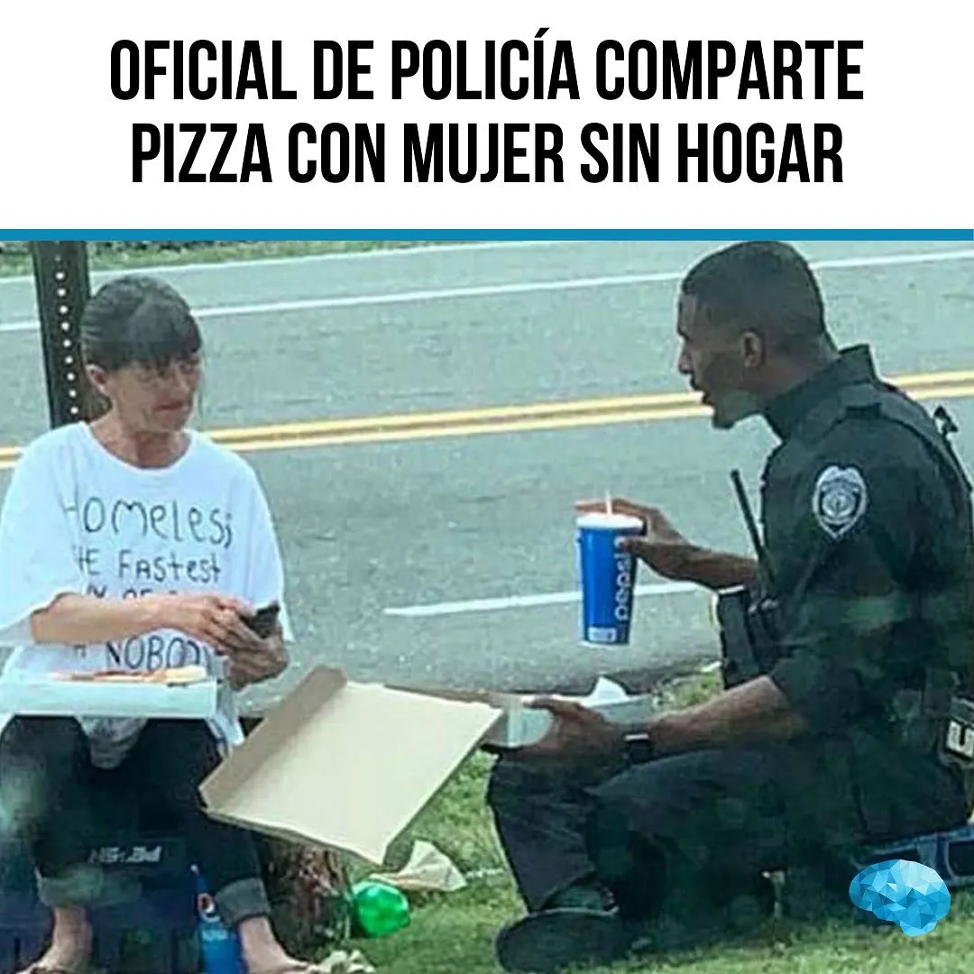 Se ve a un policía sentado en el suelo junto a una mujer sin hogar. El policía le está ofreciendo una pizza a la mujer, que parece muy agradecida. Ambos están sonrientes. En el suelo hay una caja de pizza abierta y una bebida.
